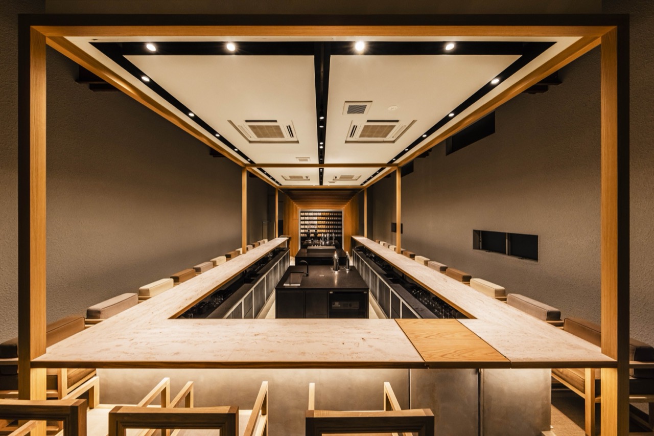 The bar is the stage, the seats are the audience · A stone counter wrapping three sides. The grammar of a sushi omakase counter, grafted onto coffee. The whole extraction becomes a performance in front of you, and watching it becomes the ground for the price. ⓒ KOFFEE MAMEYA / 14sd