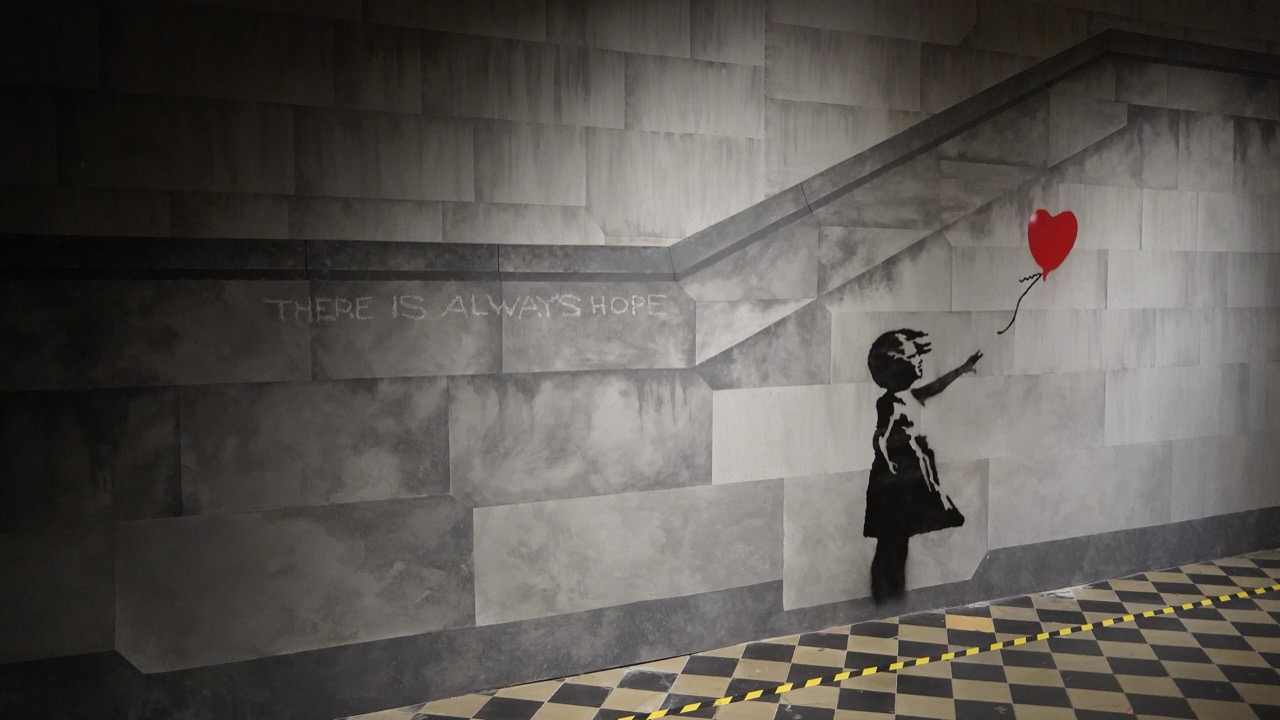 2022년 브뤼셀에서 열린 무단 순회전 The World of Banksy. 실내에 석축 벽을 그려 넣고 그 위에 '소녀와 풍선'을 다시 뿌려 놓았다. 작가가 부정해 온 바로 그 형식이다. ⓒWikimedia Commons