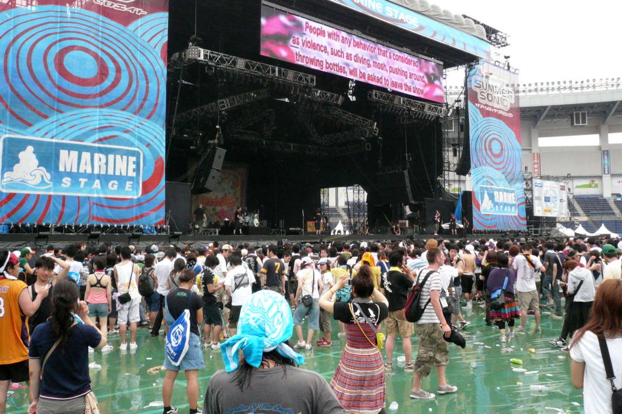 複数の好みをひとつの会場に · SUMMER SONICの野外マリンステージ。ロックで始まったが、いまはヒップホップ・EDM・J-POP・アイドルが複数のステージに分かれて立つ。切符一枚で複数のジャンルを見せて客単価を守る。ⓒWikimedia Commons