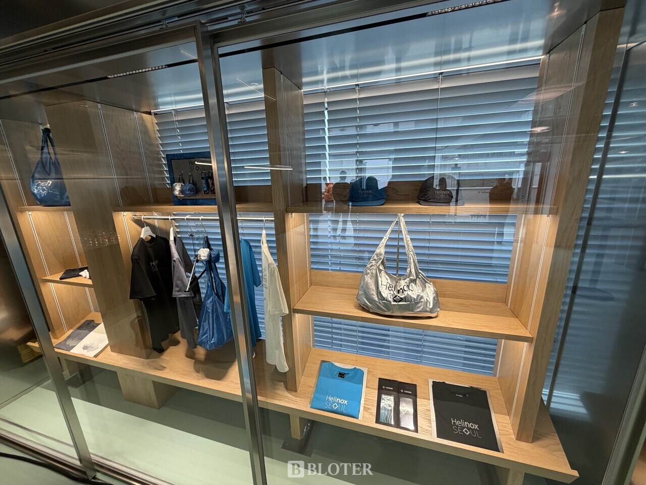 Seoul-only goods · T-shirts, bags, caps and bandanas sold only at the flagship, gathered in a glass case. ⓒBloter