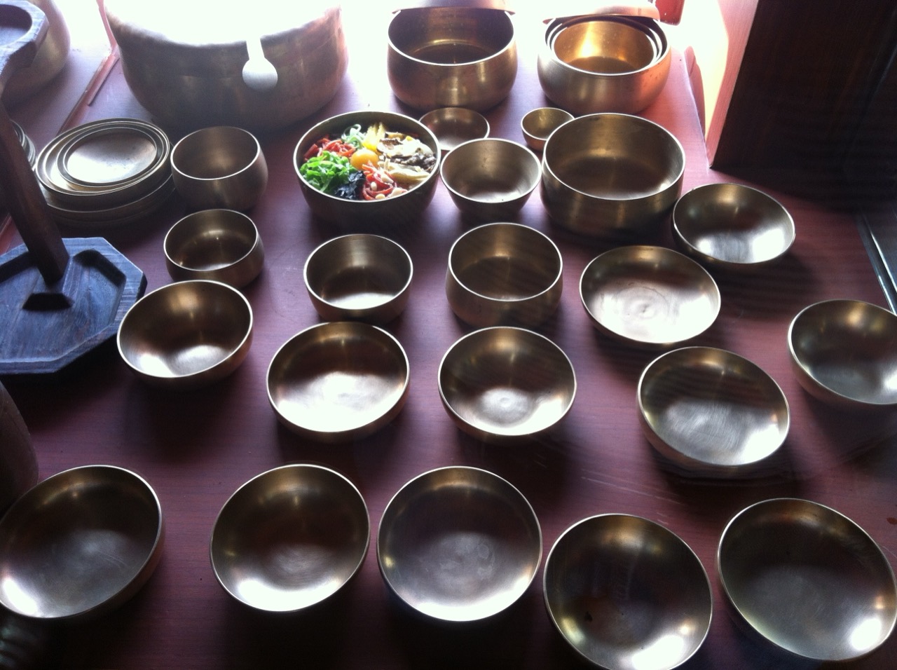 方字(パンチャ)真鍮器 · 叩いて作った真鍮の器が大きさ順に並ぶ。ビビンバが入っているのは一つだけ。展示室の外で撮った写真だ。ⓒsolanee · CC0