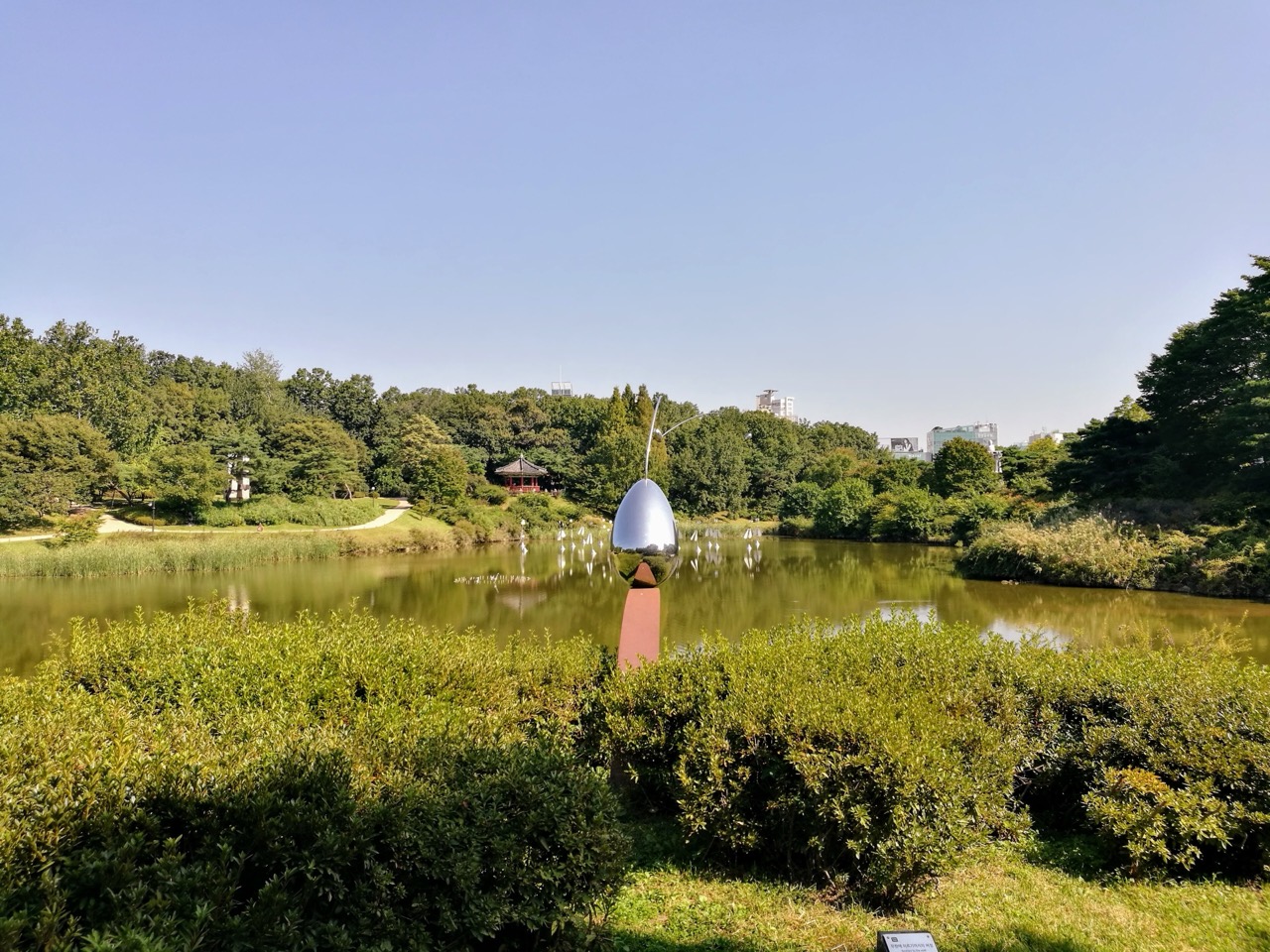 공원 안 호수 · 올림픽공원 안 호숫가. 은색 조각 너머로 정자가 보인다. ⓒTeemeah · CC BY-SA 4.0