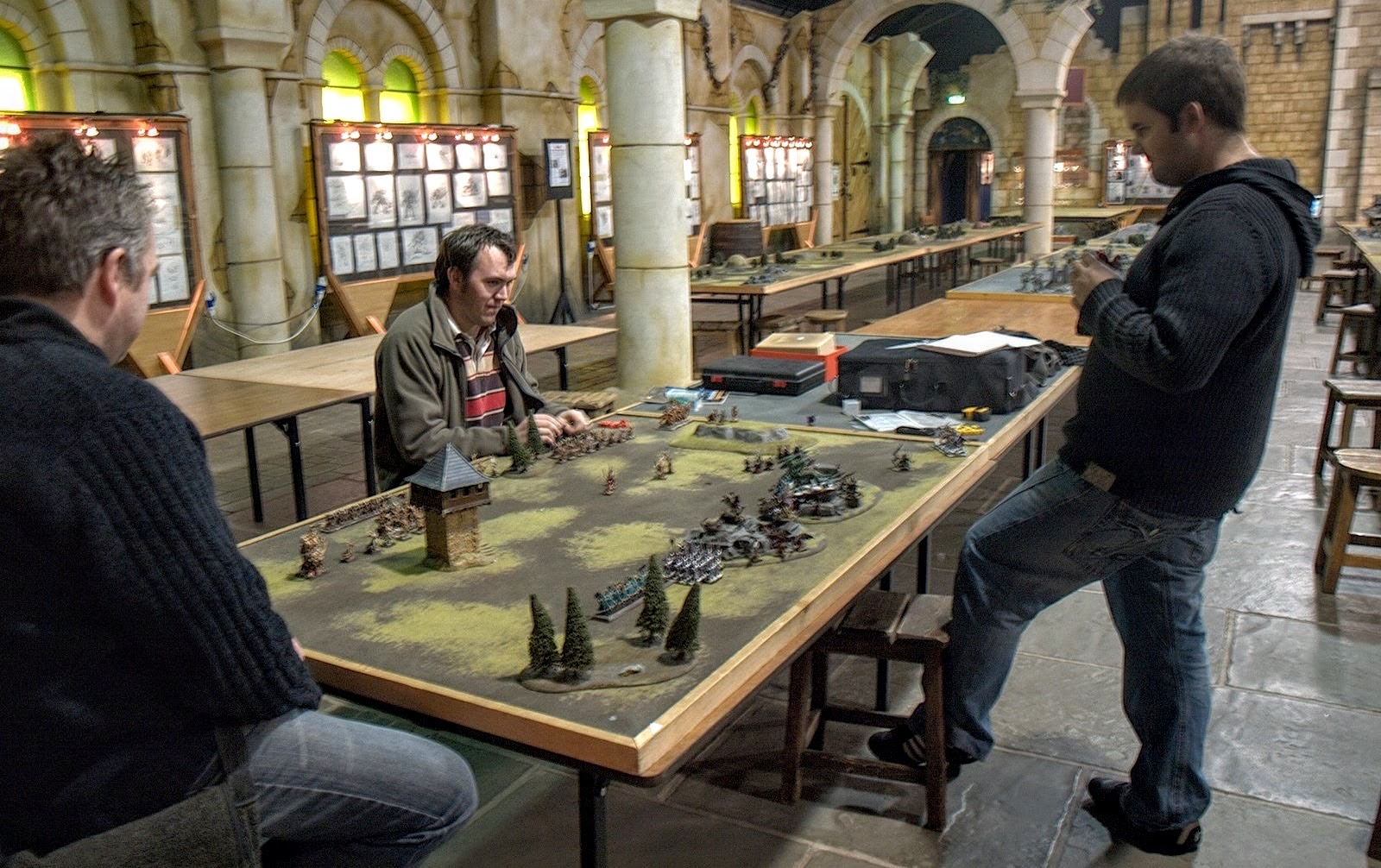 노팅엄 본사 게임 홀 · Games Workshop 본사의 게임 홀. 긴 탁자 위에 지형과 군대가 깔려 있다. ⓒJesusbella · CC BY-SA 4.0