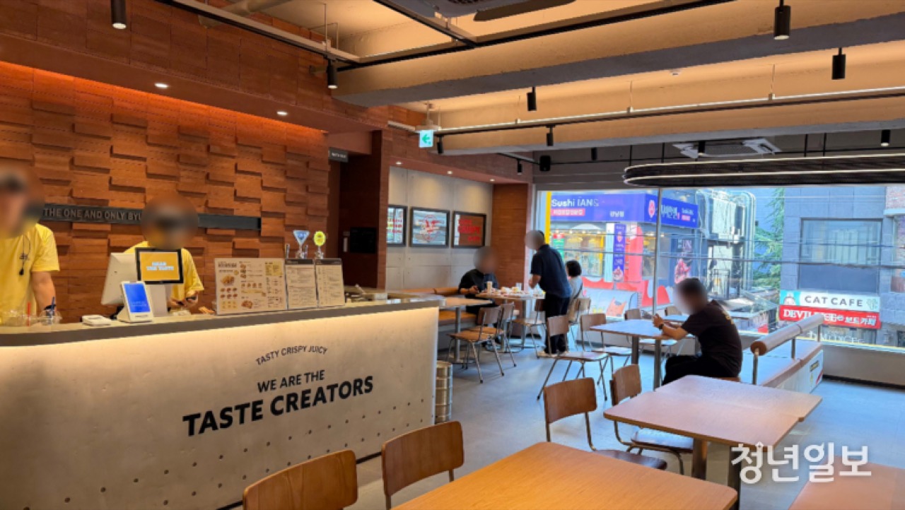 낮 시간 · 주문대에 WE ARE THE TASTE CREATORS라 적혀 있다. 창밖은 골목 건너 상가. ⓒ청년일보