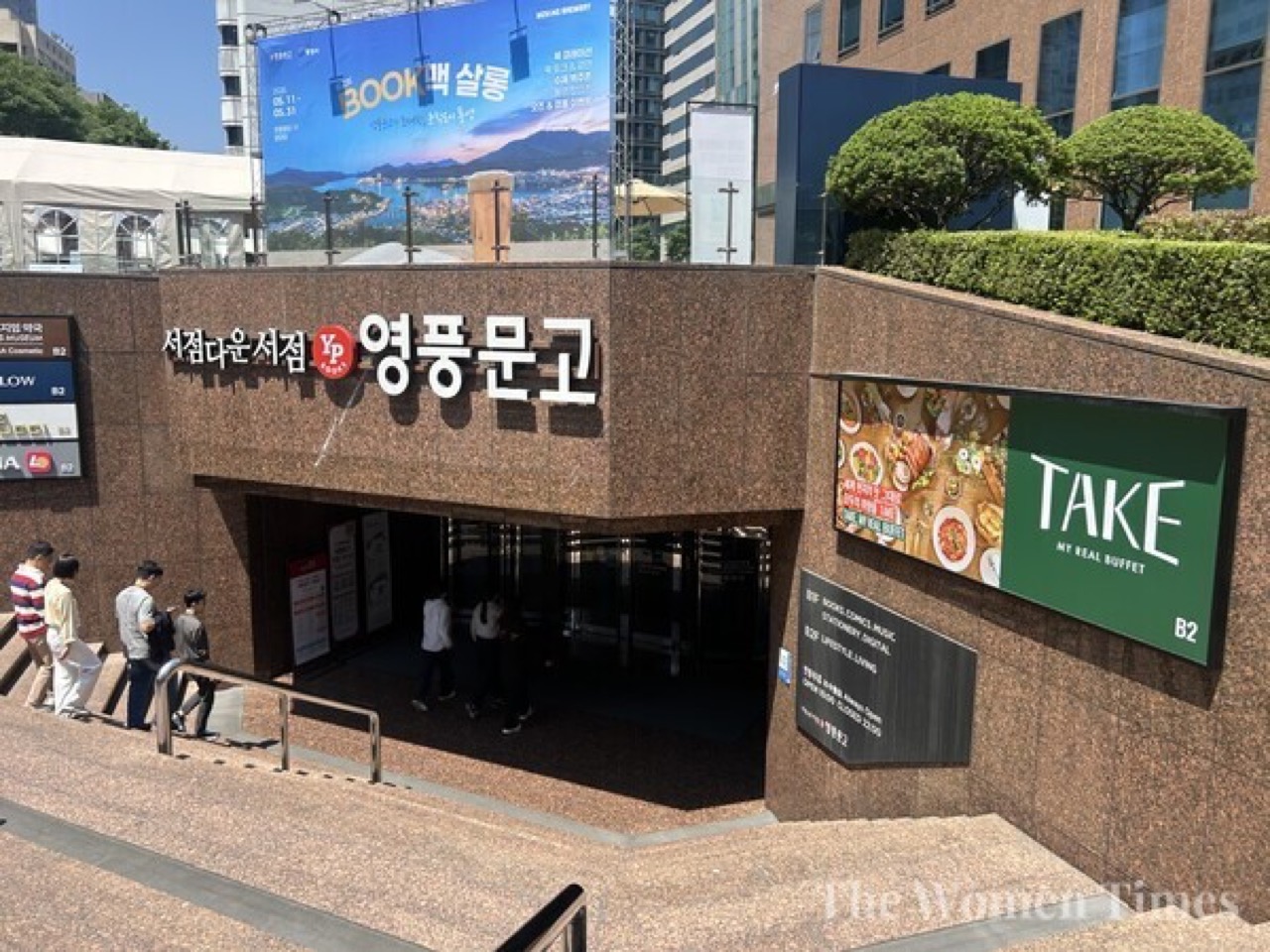 지상에서 보이는 것 · 서점 입구 옆 벽면에 걸린 안내판 하나. 매장은 이 계단 아래. ⓒ우먼타임스