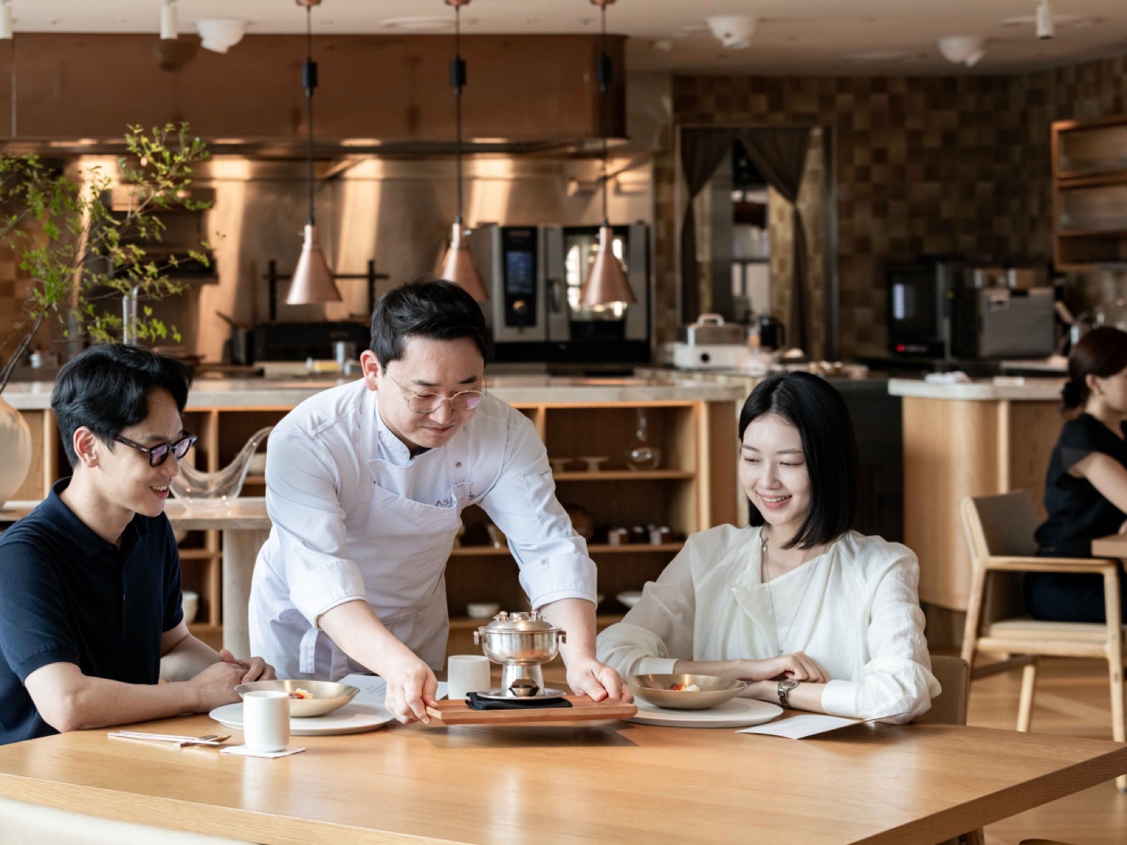 오픈키친 앞 테이블 · 셰프가 손님 자리에 신선로를 내려놓는다. ⓒ한화푸드테크