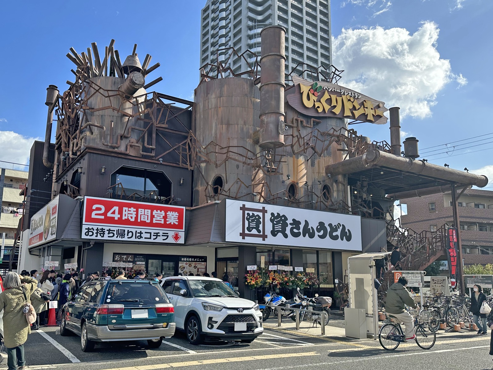 大阪・今福鶴見店の行列 · 1階の庇に24時間営業の横断幕が掛かる。建物の上部には、ハンバーグチェーン「びっくりドンキー」の看板装飾が見える。ⓒTokumeigakarinoaoshima · CC BY-SA 4.0