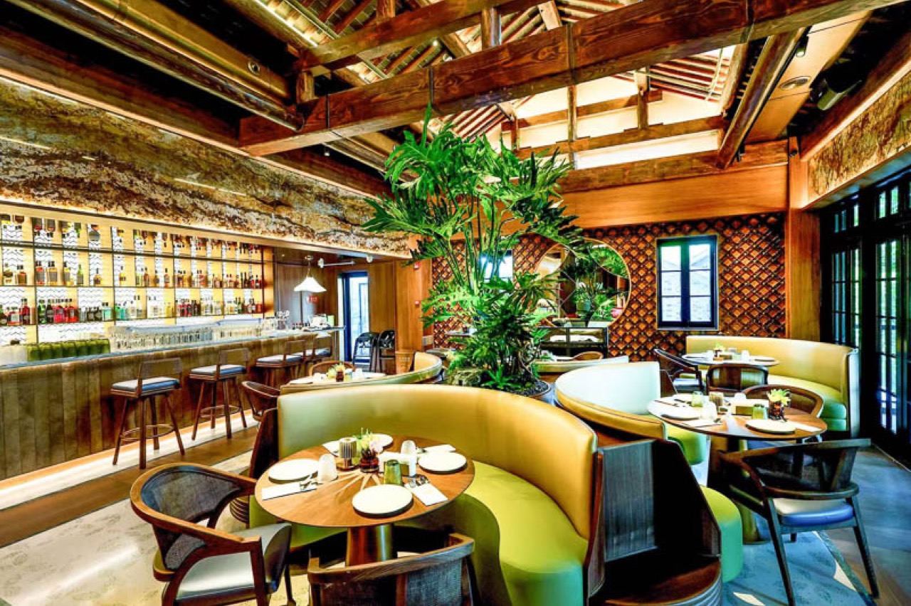 The bar and dining room · The bar and green sofa seating under exposed rafters. ⓒNOMFLUENCE