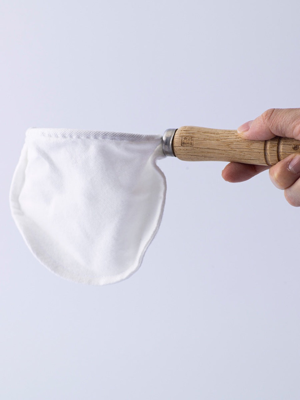 종이가 붙잡는 것을 천은 통과시킨다 · 플란넬 필터. 사진은 도쿄 다이보 커피점(大坊珈琲店)의 형태를 이어받은 제품이다. 천은 매번 삶고 물에 담가 보관해야 해서, 도구가 아니라 관리 대상에 가깝다. ⓒKurasu Kyoto
