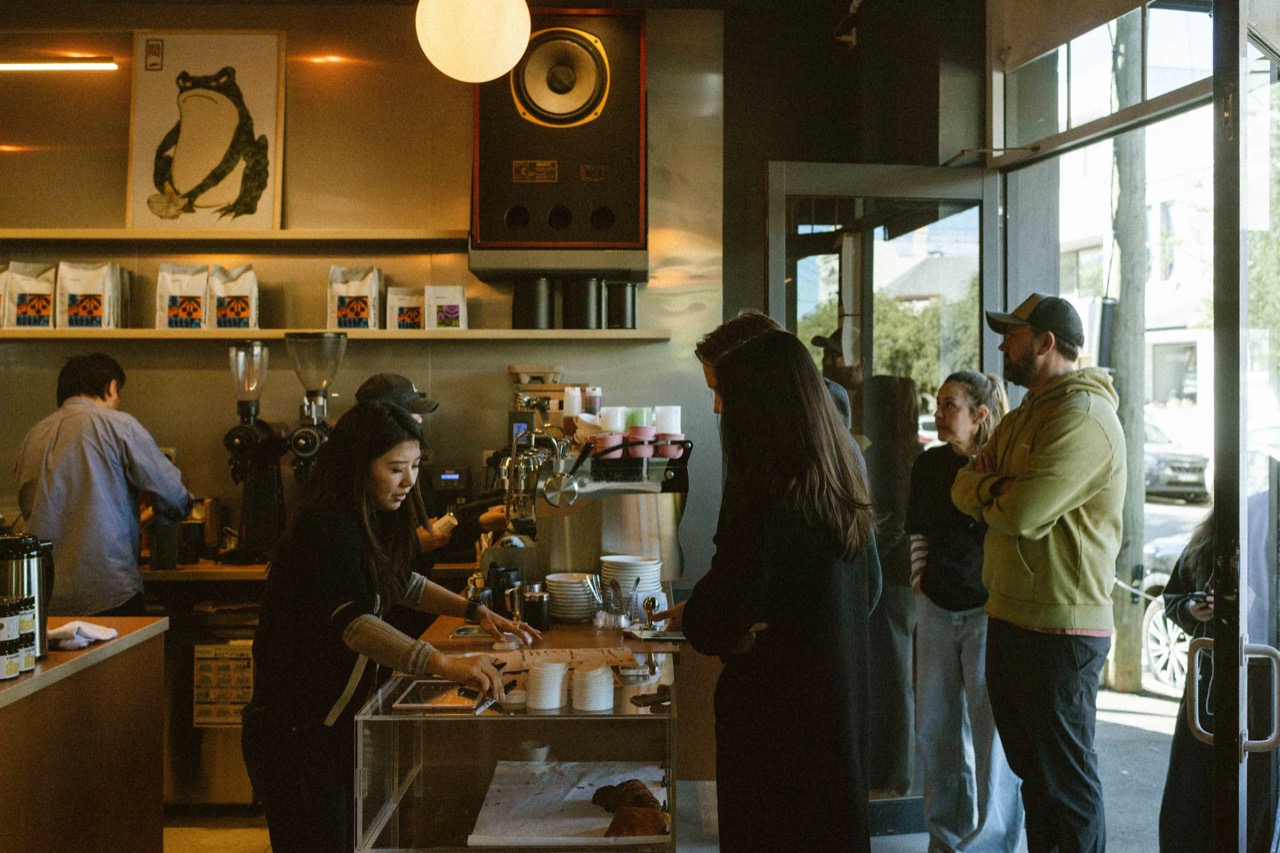One speaker · The speaker mounted above the bar, with a frog scroll beside it. The bags on the shelf are retail coffee. ©Yusuke Oba · Broadsheet