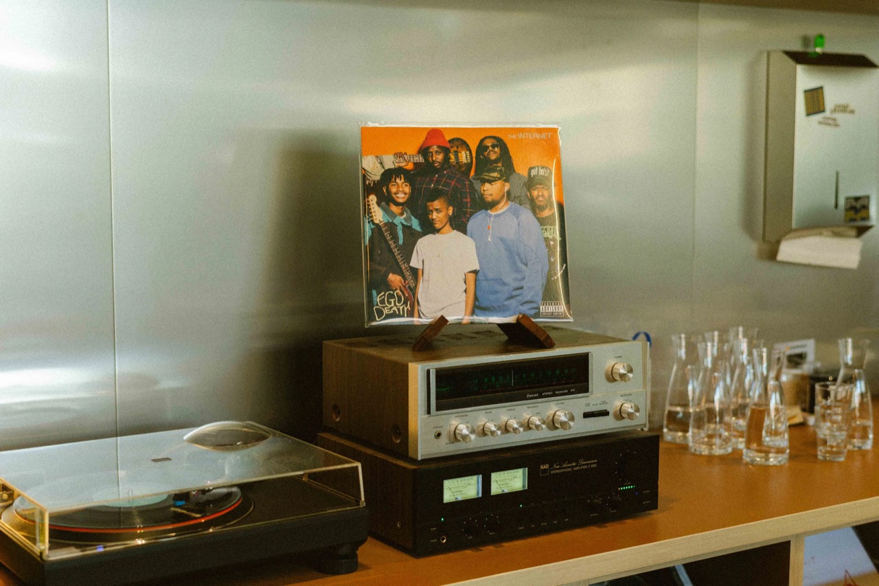 What is playing now · Receiver and amplifier stacked next to the turntable, the sleeve of the record in play propped on a wooden stand. Glass water carafes on the right. ©Yusuke Oba · Broadsheet