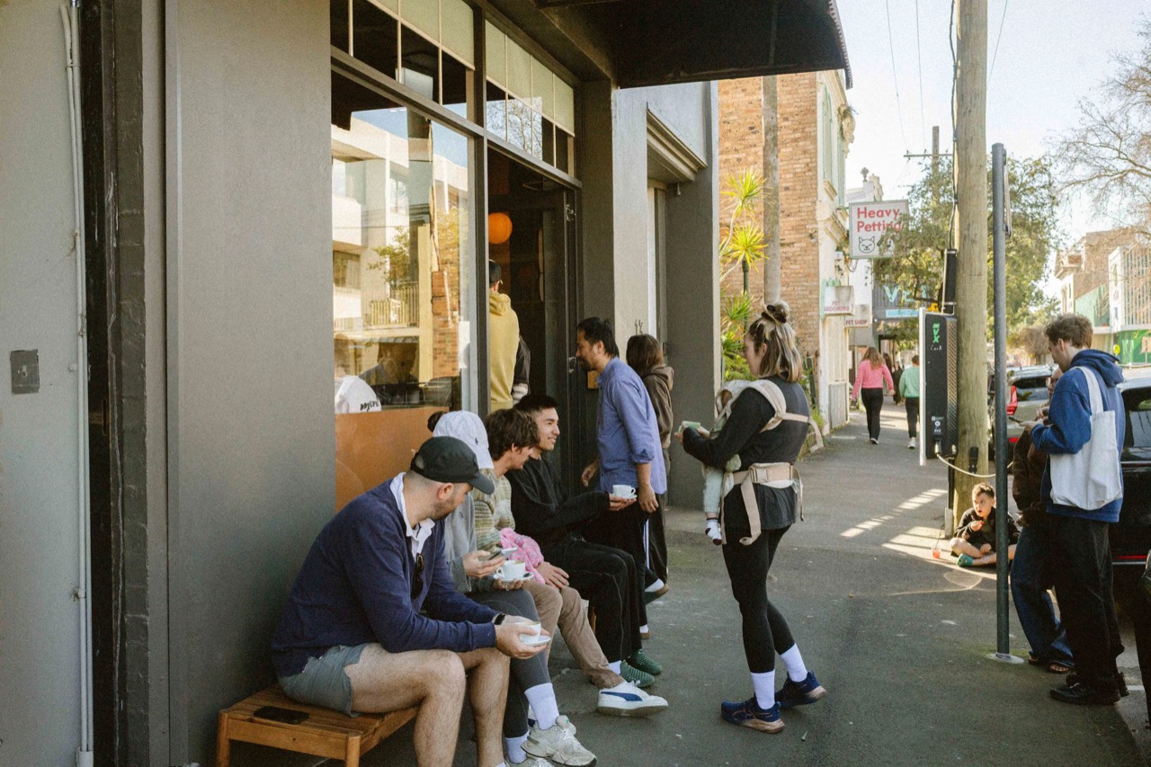 The footpath is seating too · A timber bench on the footpath and customers standing at the door. Across the road is the local pet shop. ©Yusuke Oba · Broadsheet