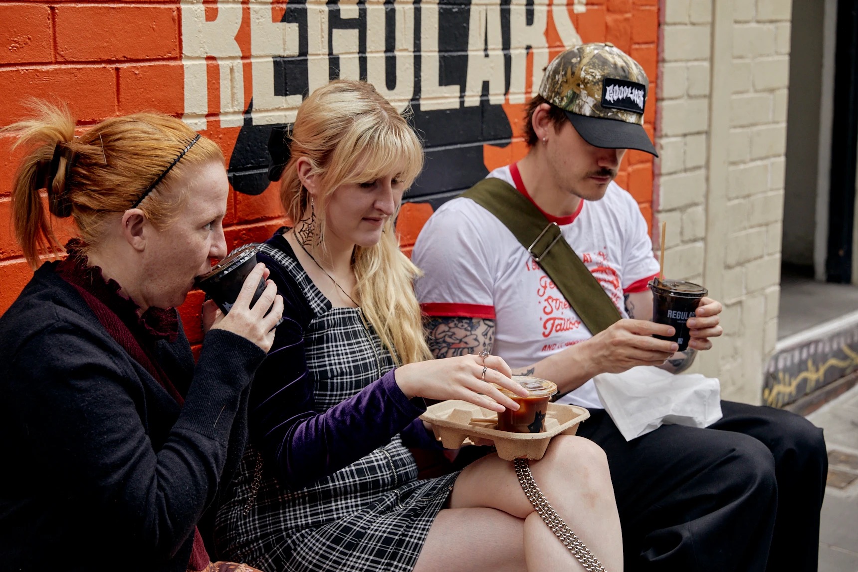 가게 벽 앞의 손님 · 가게 벽 앞에 앉아 유리잔을 든 손님들. ⓒCasey Horsfield · Broadsheet