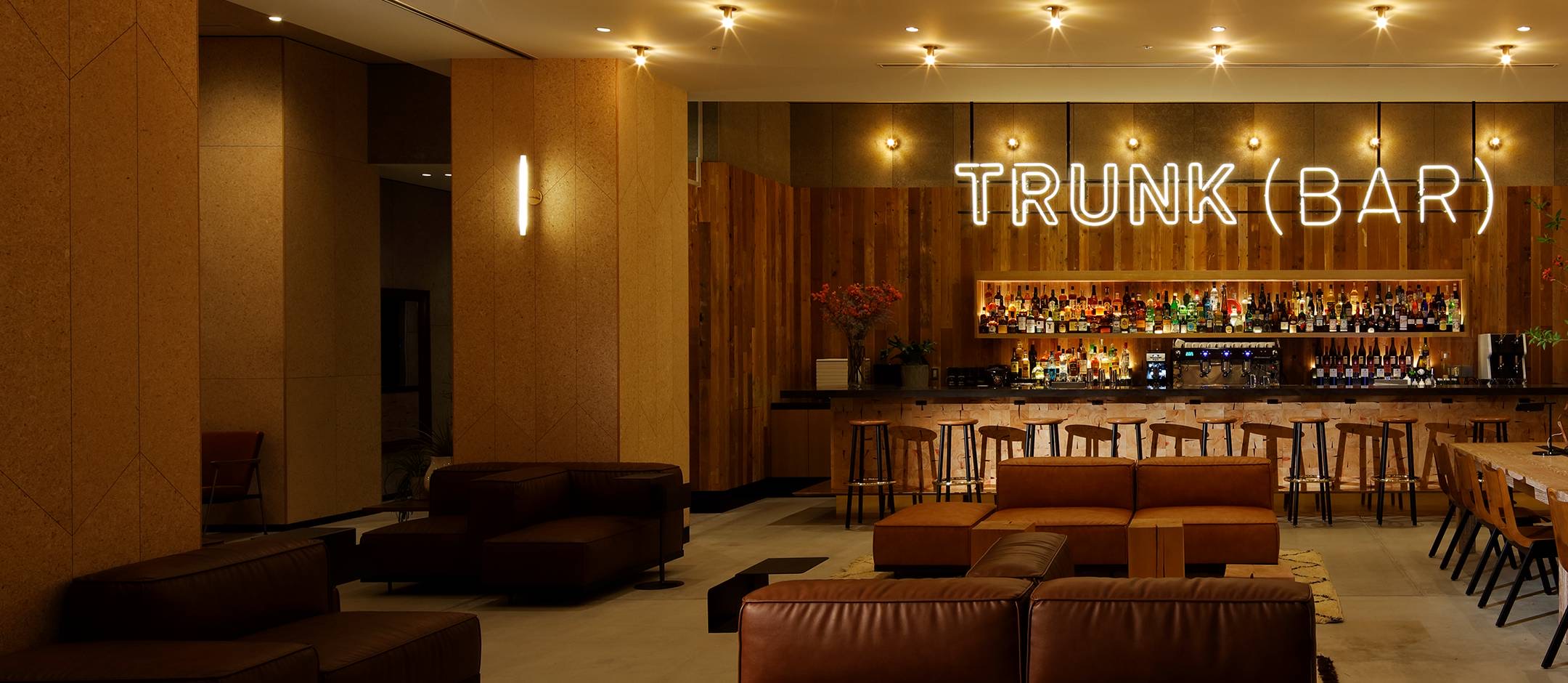 TRUNK(BAR) · 1층 로비 라운지. 옛 목재를 이어 붙인 벽 앞에 바 카운터가 서고, 가죽 소파가 로비를 나눠 쓴다. ⓒTRUNK(HOTEL)