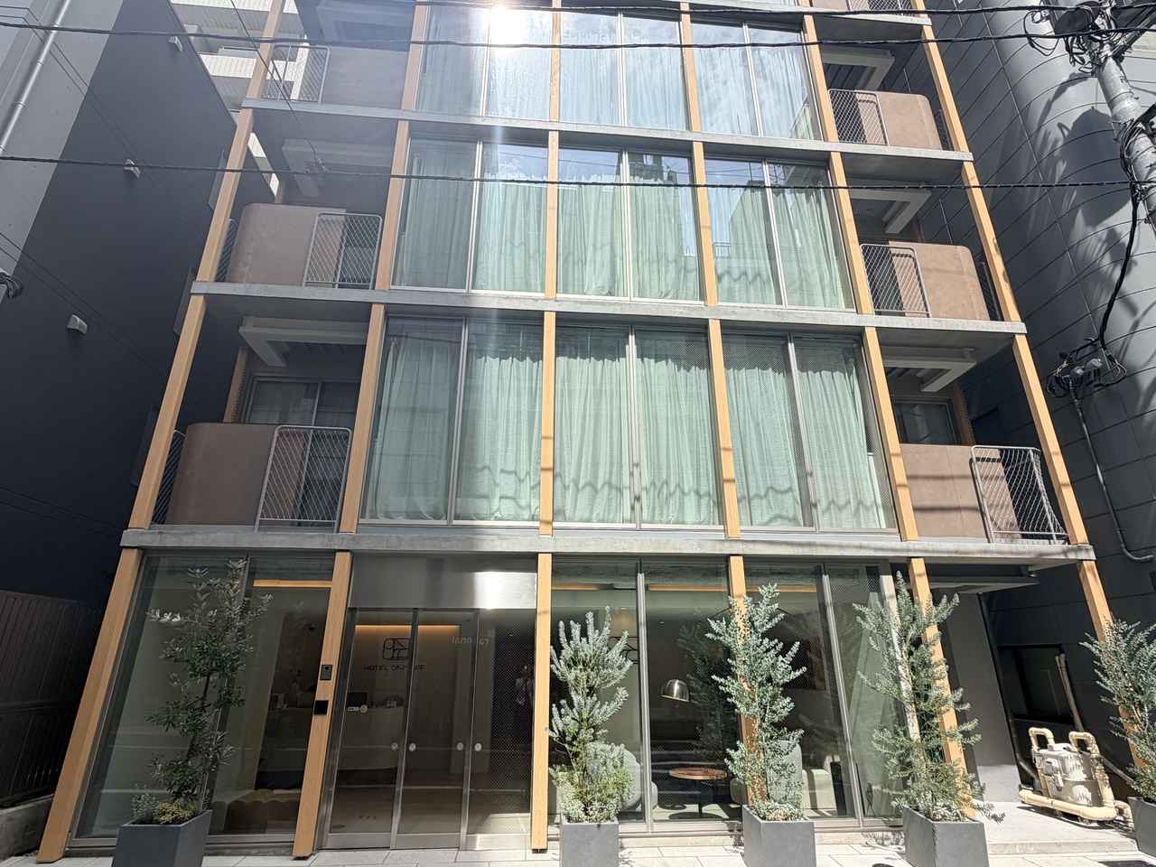 34㎡ 트윈 · 침대 머리 쪽 벽을 나뭇결 판재로 덮고, 창가에 줄무늬 쿠션을 이어 붙인 긴 벤치를 놓았다. ⓒトグルホールディングス / PR TIMES