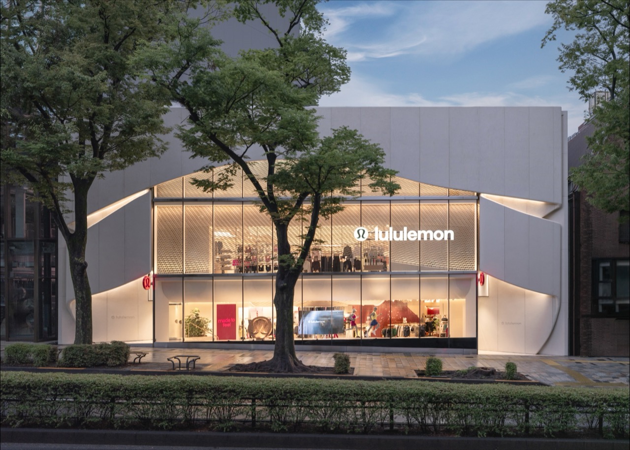 After dark the inside is all visible · With the lights on across two floors of glass, the wave ceiling and the red wall read straight from the street. ⓒlululemon