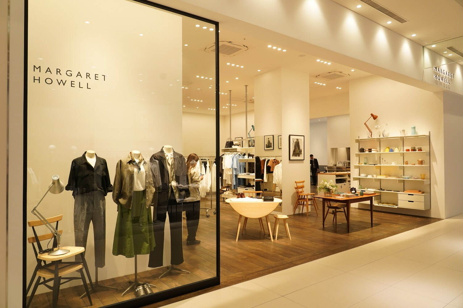 Grand Green Osaka storefront · Mannequins and a wooden chair stand together behind the glass. ⓒFASHION PRESS