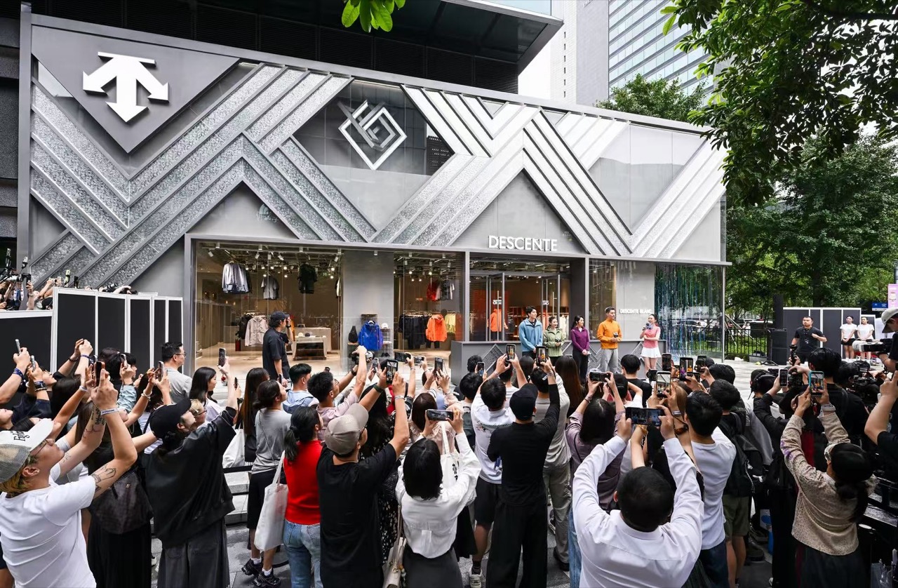 개점 날 매장 앞 · 사선 띠 외벽을 향해 휴대전화를 든 사람들. ⓒDESCENTE China·PR Newswire