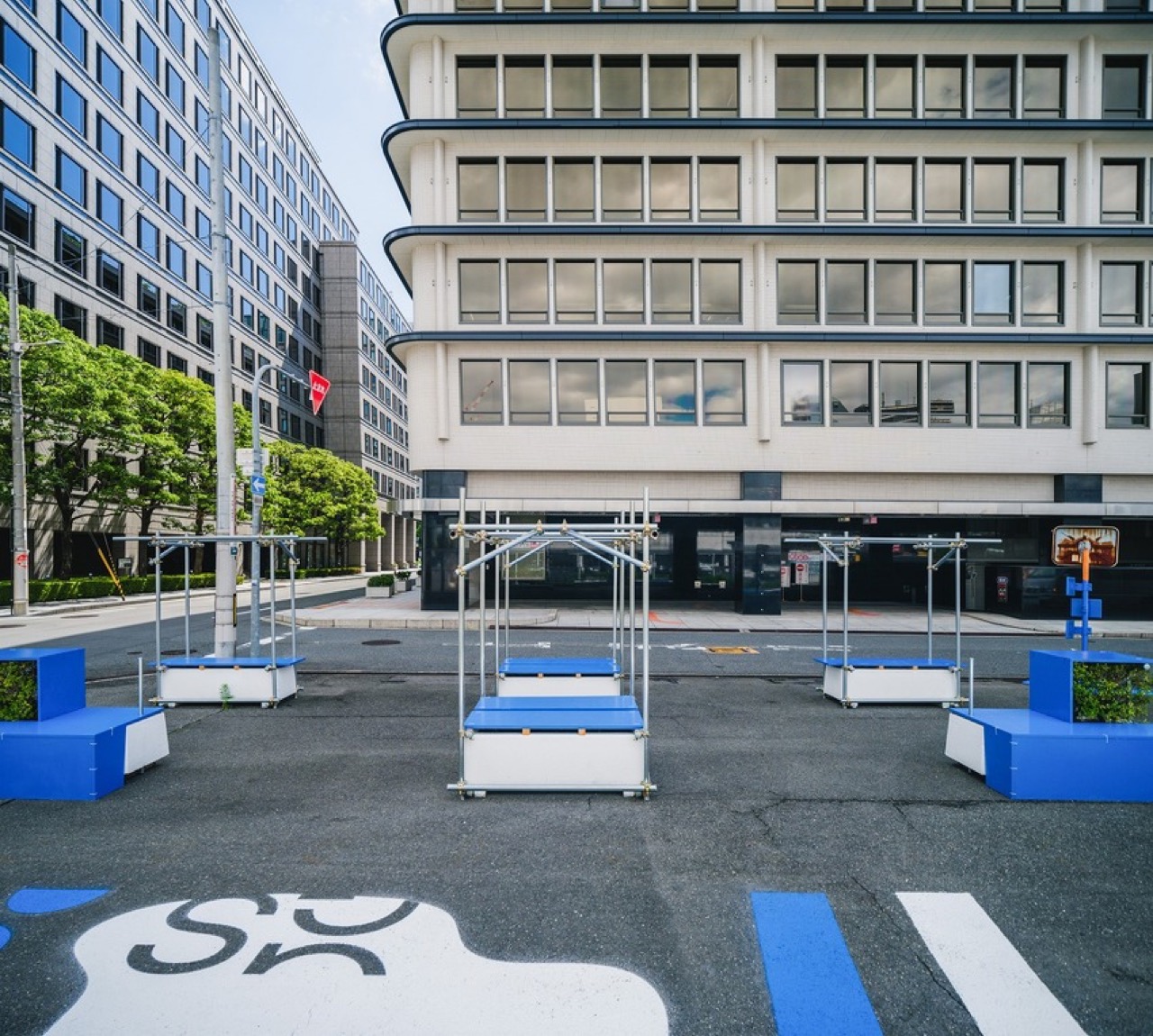 道の向こうまで抜ける視線 · 敷地と道の間に塀はない。向かいには白い横帯を巡らせた建物が立つ。ⓒYosuke Ohtake
