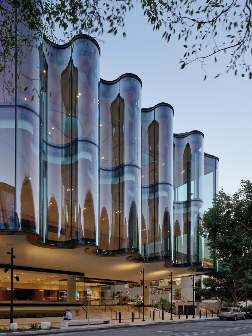 Sky caught in the curved glass · A single curved unit stands up to 7.1 metres tall. The black pattern at the base is ceramic printing that cuts solar gain. ⓒChristopher Frederick Jones · via Dezeen