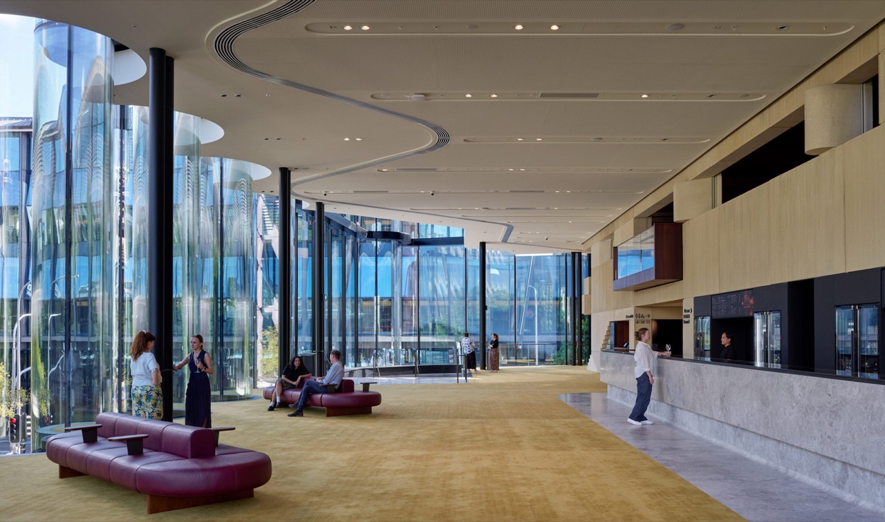 The gold-carpeted foyer · On the left, the rippling glass facade. On the right, the sand-coloured precast wall. ⓒChristopher Frederick Jones · via Dezeen