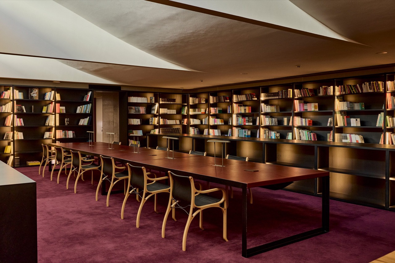 最上階の図書室 · 傾斜した天井の下に長いテーブルがひとつ。壁はすべて書棚。©Andrey Arakelyan・Dezeen掲載