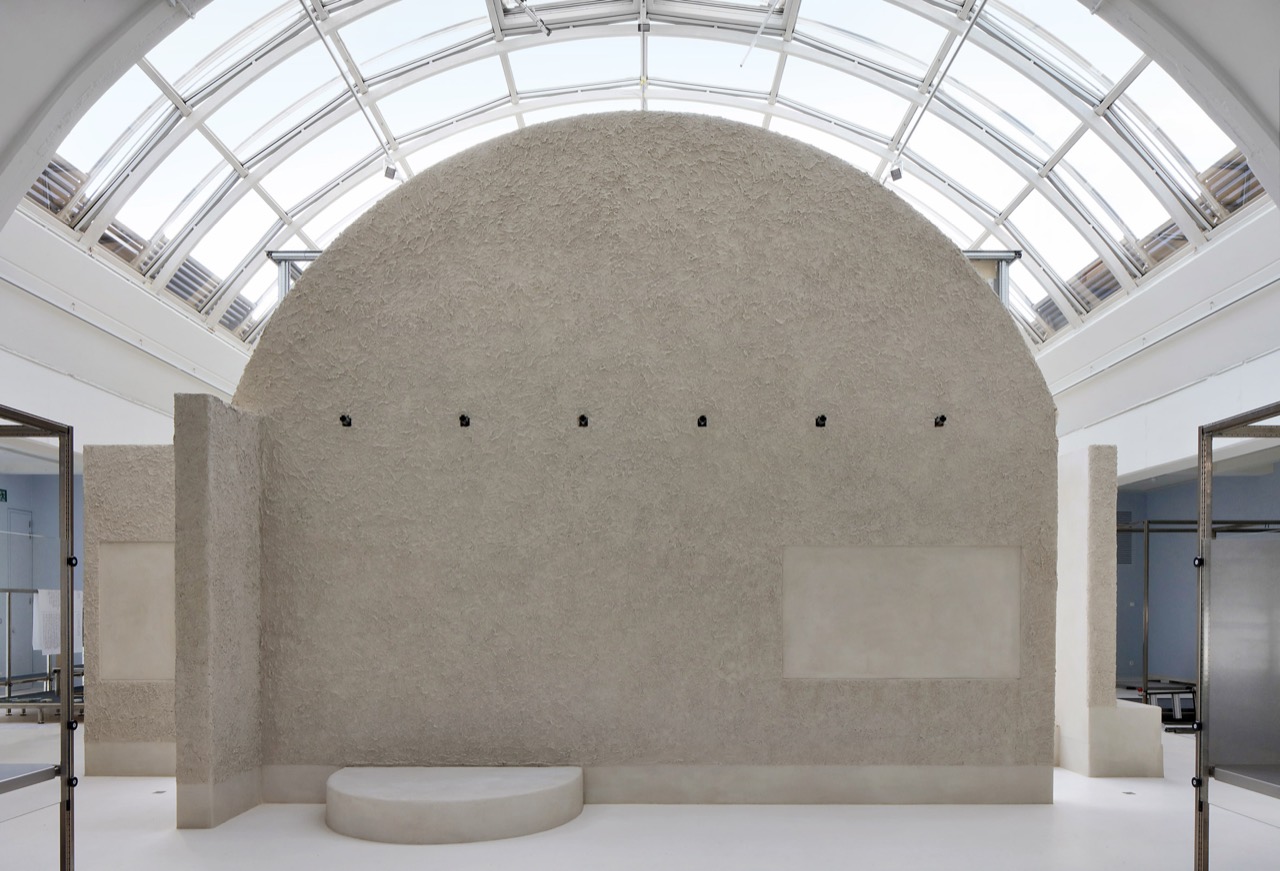 ガラス屋根の下の土壁 · 土で塗った壁一枚が大きな展示室を仕切る。©Filip Dujardin・Dezeen掲載